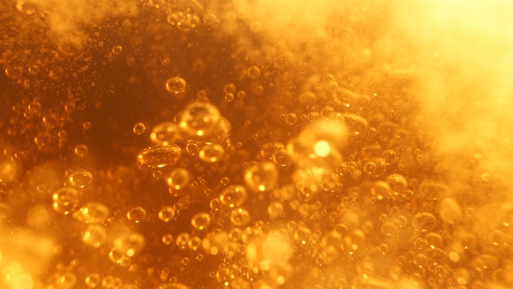 Macro carbonation bubbles inside golden lager used in a tabletop beer advertising campaign case study.