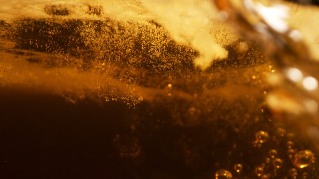 Macro carbonation bubbles rising through golden lager during a tabletop beer advertising campaign case study.