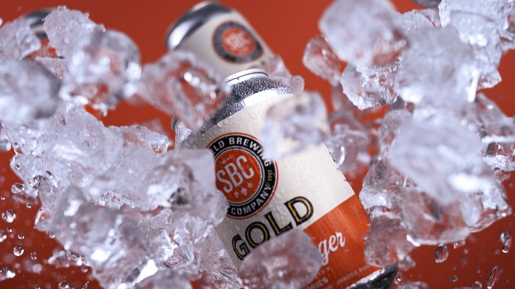 Gold Light Lager can surrounded by flying ice cubes during a tabletop advertising campaign shoot.